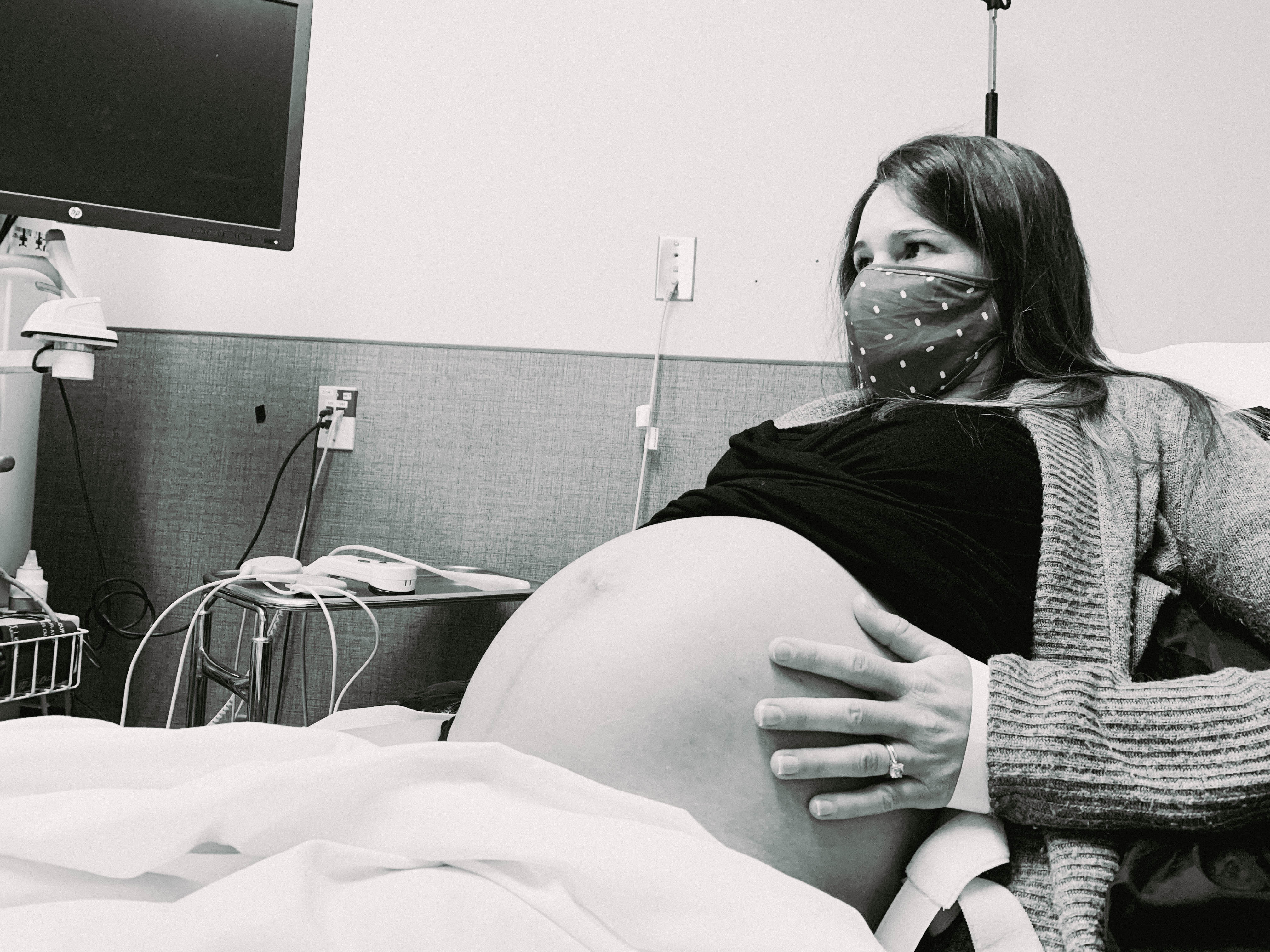 Pregnant woman in a hospital bed wearing a polka dot mask during the early stages of labor at the start of the COVID-19 pandemic